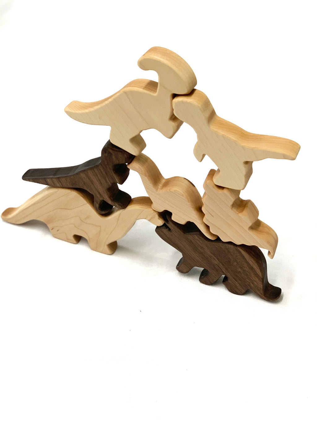 Set of natural and dark wooden dinosaur toy figurines stacked on white background for imaginative play