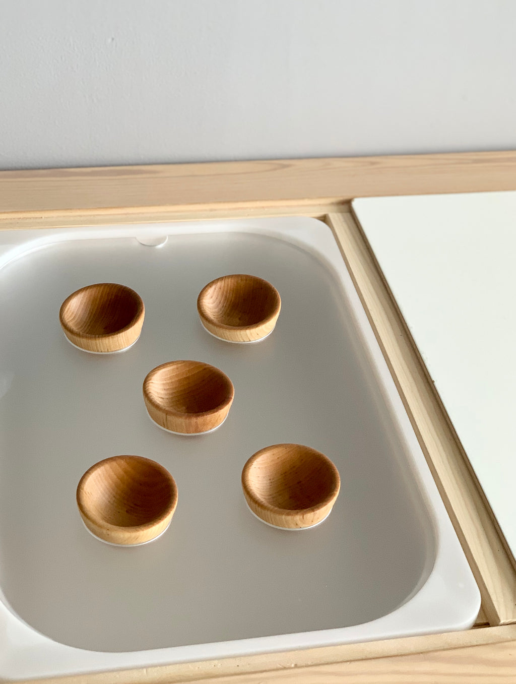 Close-up of Tinker Pot Flisat Table Top Insert with five small wooden bowls on white acrylic tray and maple plywood frame