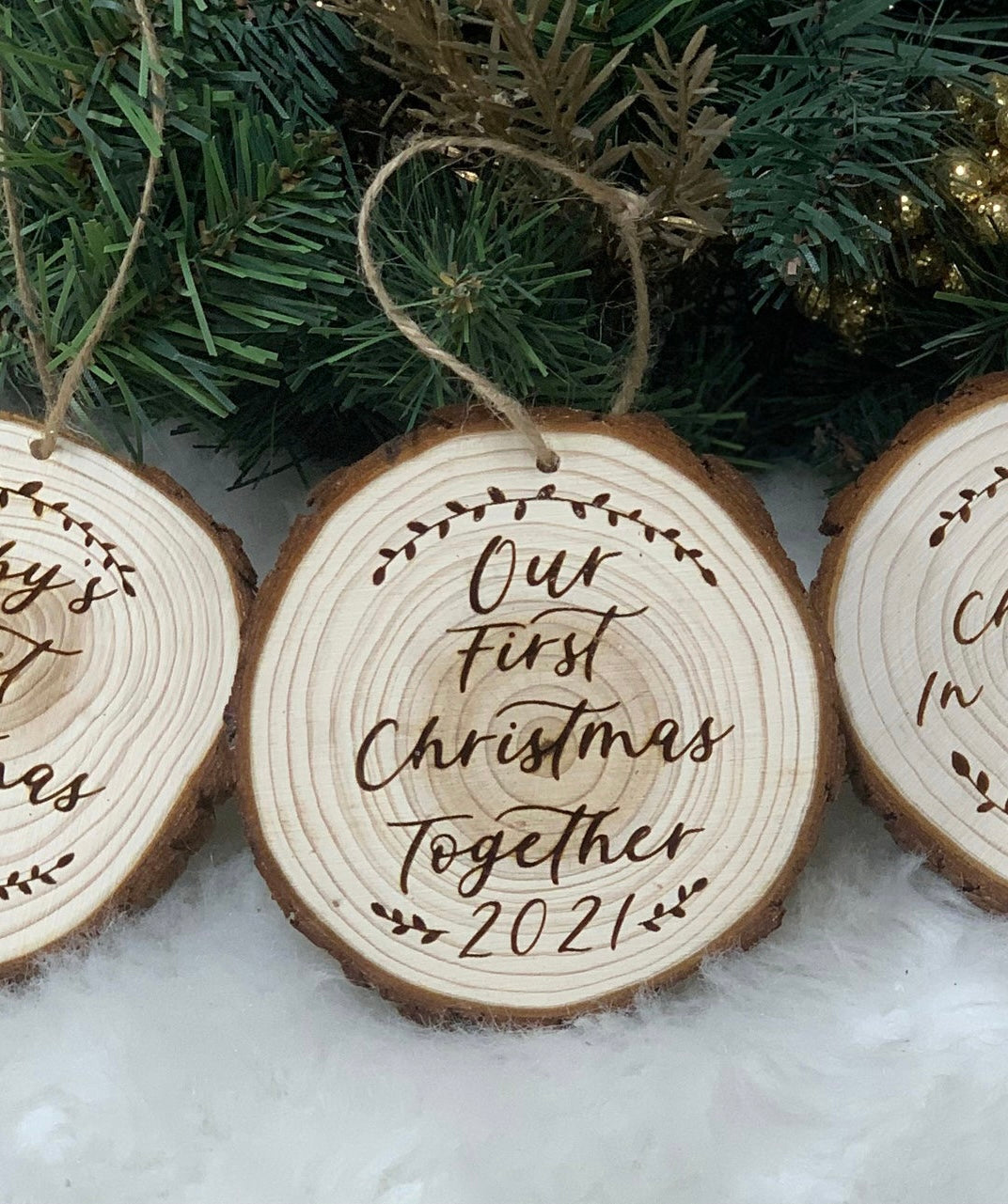 Wooden Christmas ornament engraved Our First Christmas Together 2021 hanging on a tree branch with pine needles