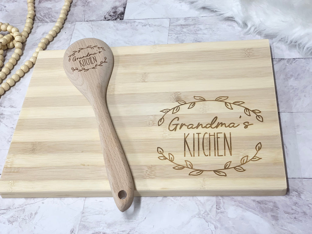 Personalized bamboo cutting board and wooden spoon engraved with Grandma’s Kitchen and decorative leaf design