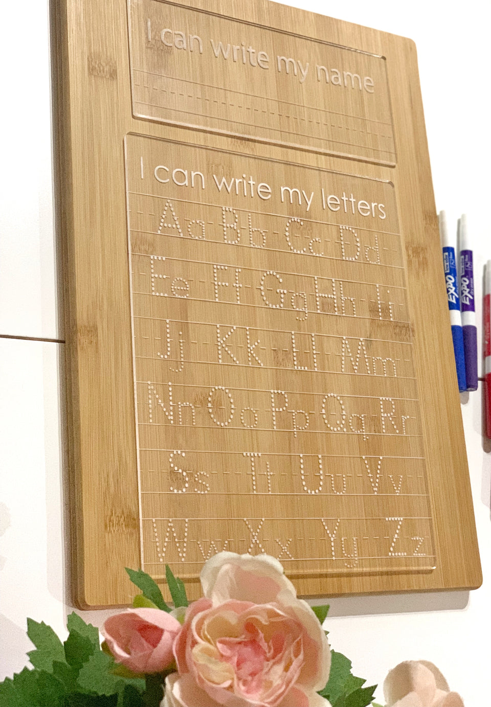 Natural wooden acrylic dry erase tracing board engraved with uppercase and lowercase letters and name writing section with markers nearby