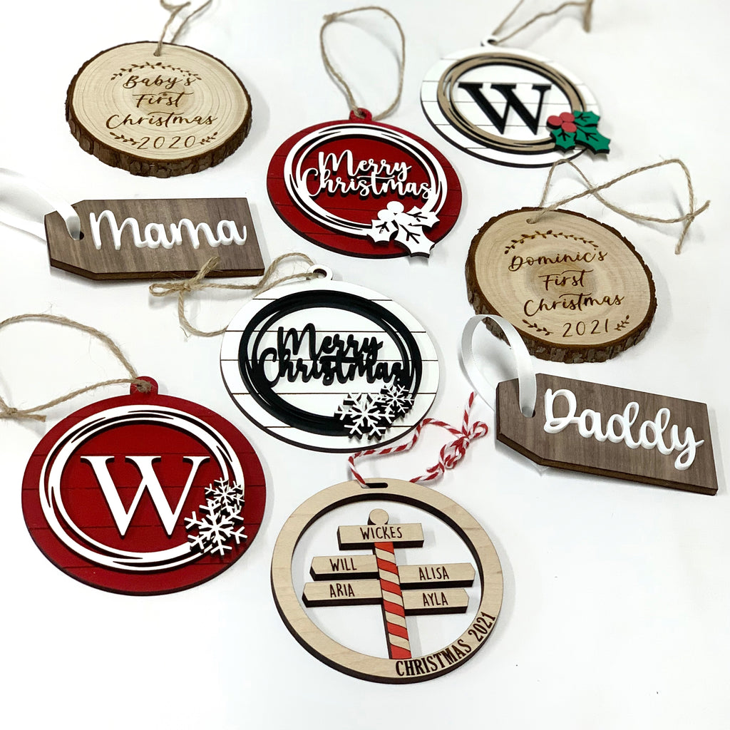 Assorted personalized wooden Christmas ornaments with names and holiday greetings on white background