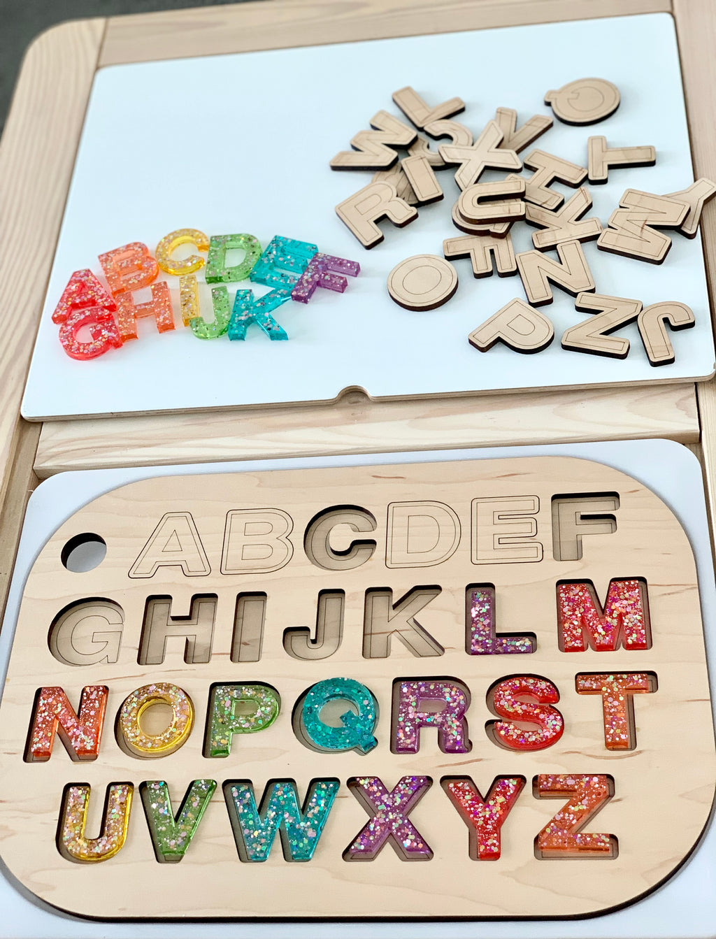 Uppercase alphabet puzzle insert with colorful resin letters and natural wood letter cutouts on Flisat table top
