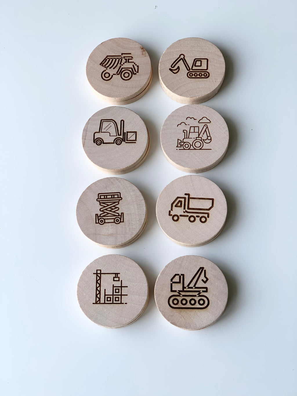 Set of natural wooden discs with engraved brown construction vehicle and work site illustrations on white background