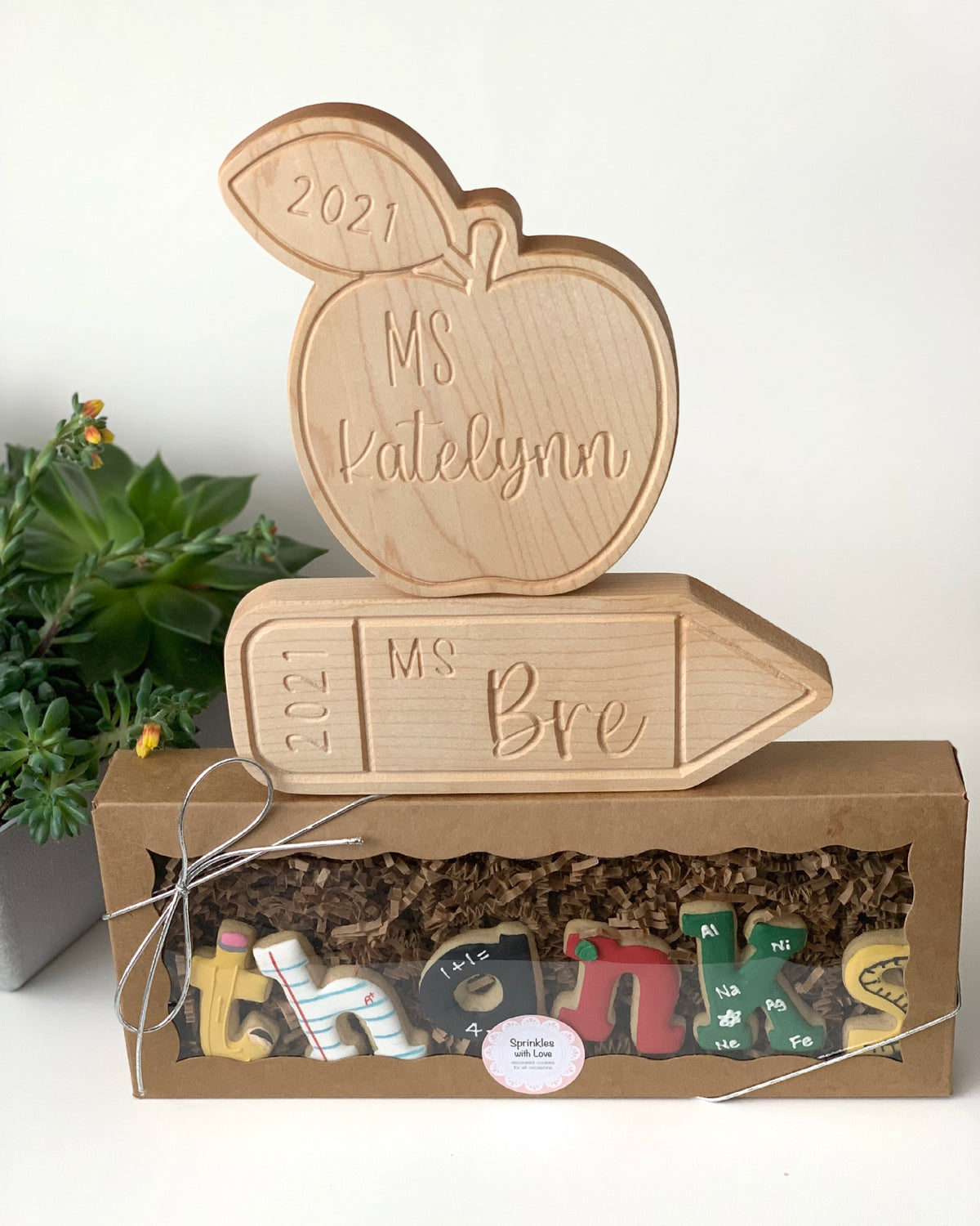Personalized wooden apple and pencil name plates engraved with teacher names and year on natural wood background