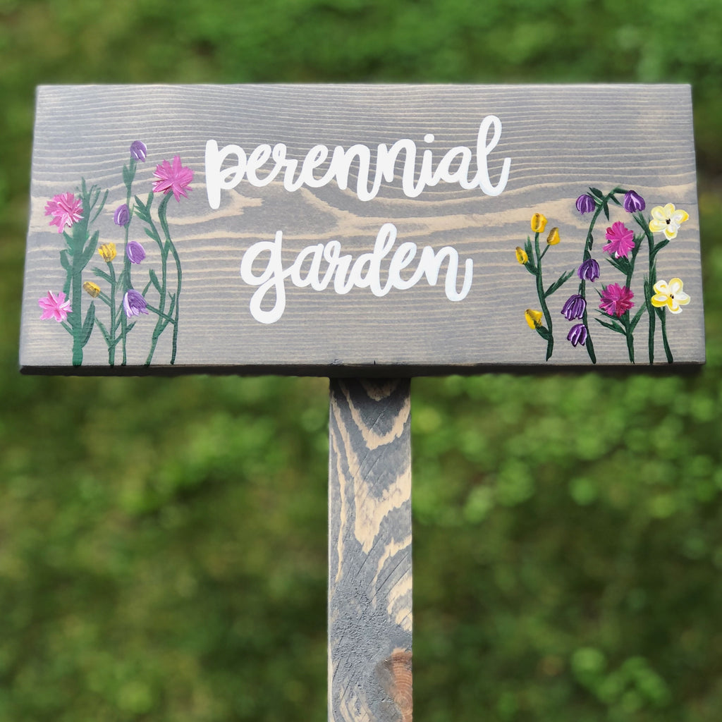 Custom wooden garden sign painted gray with white cursive letters and colorful floral illustrations on wood grain background