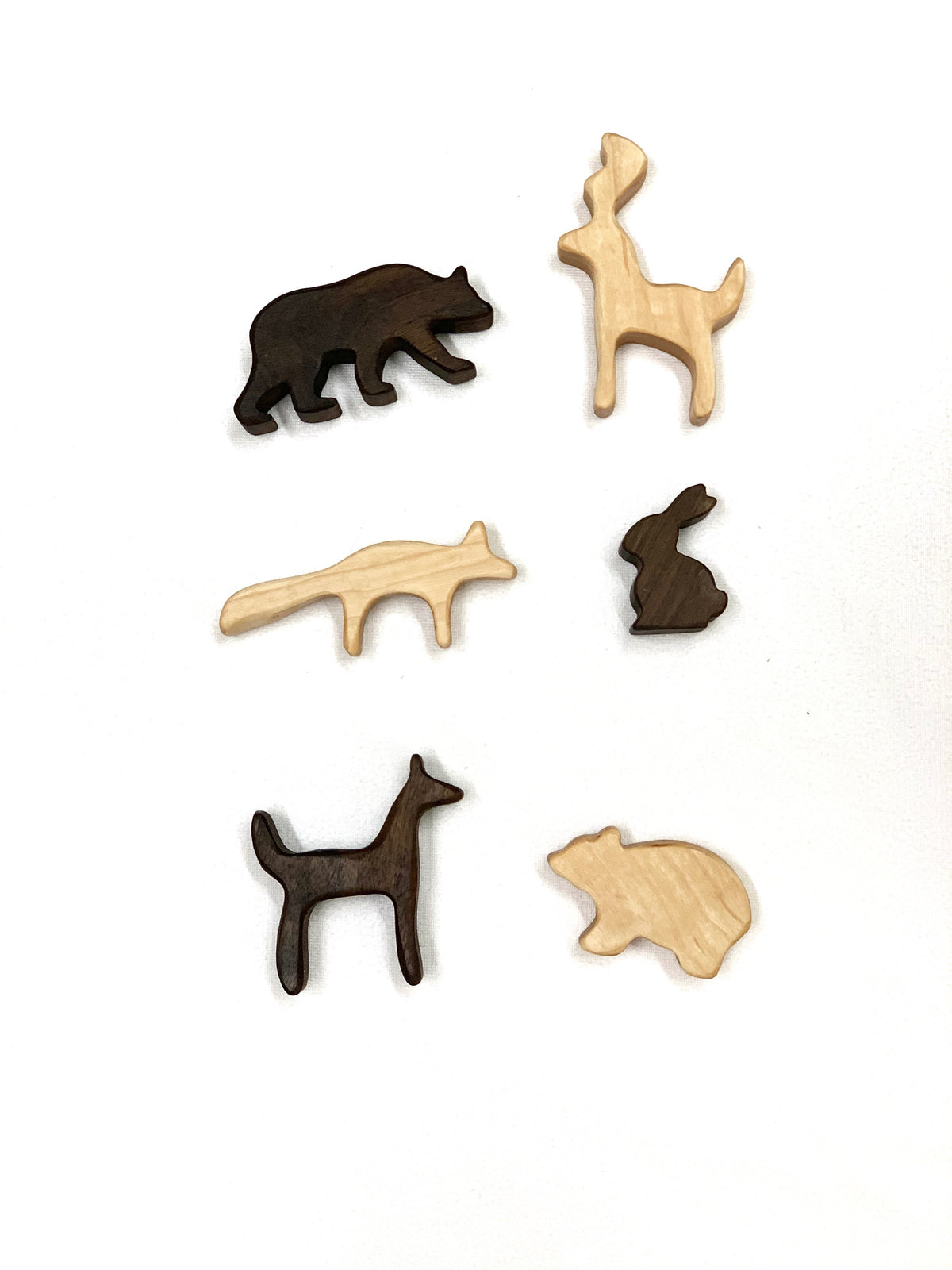 Small wooden woodland animal toy figurines in light and dark wood on white background