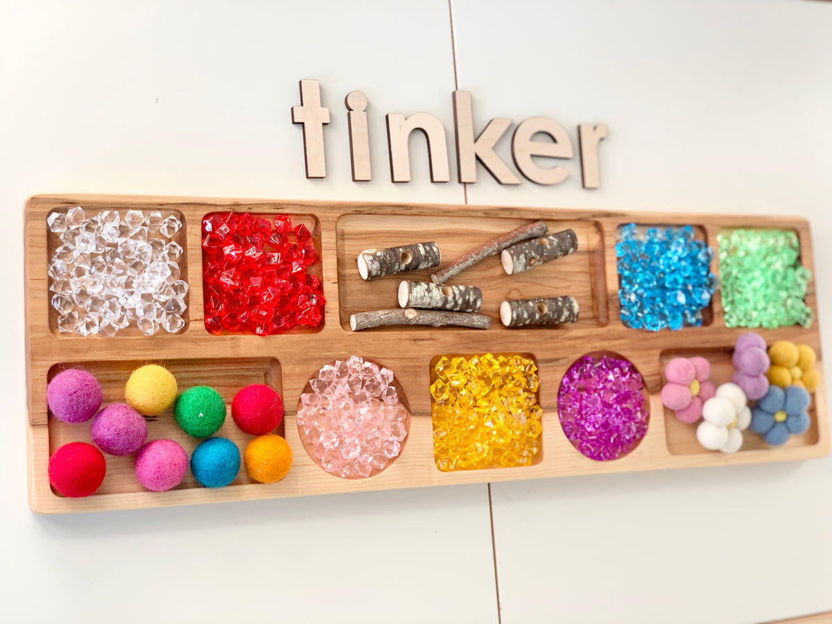 Extra large wooden tinker tray with colorful craft supplies including pom poms, plastic gems, and wooden sticks on white background