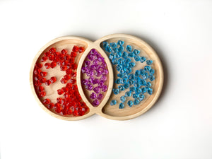 Natural wooden Venn Diagram tinker tray with red, purple, and blue translucent sensory gems on white background