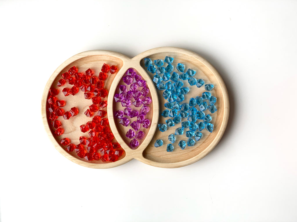 Natural wooden Venn Diagram tinker tray with red, purple, and blue translucent sensory gems on white background