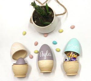 Set of three personalized hollow wooden Easter eggs in natural and pastel colors with candy and small decorations inside