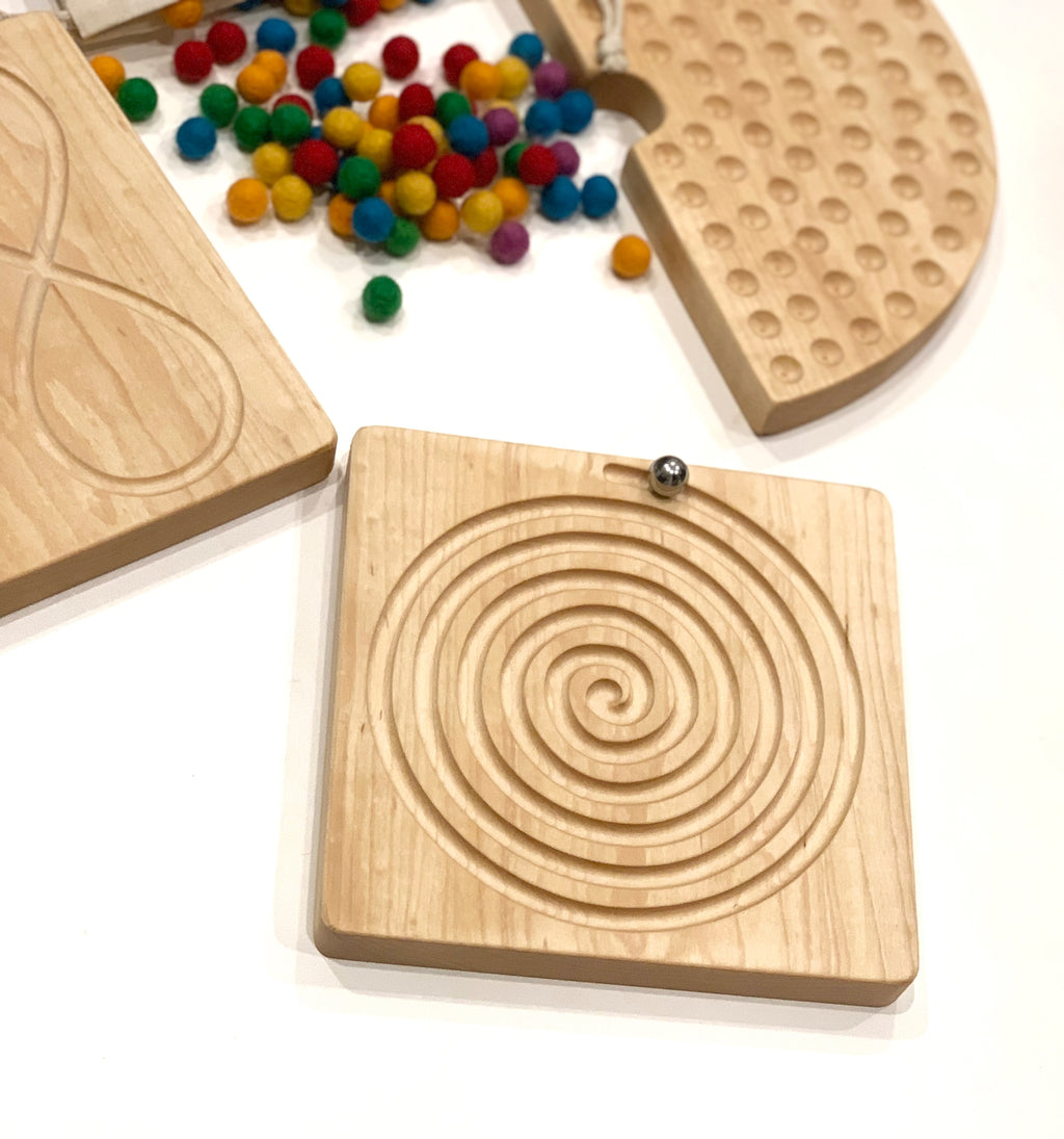 Square Canadian maple wooden labyrinth tracing board with engraved spiral path and small metal ball on white surface