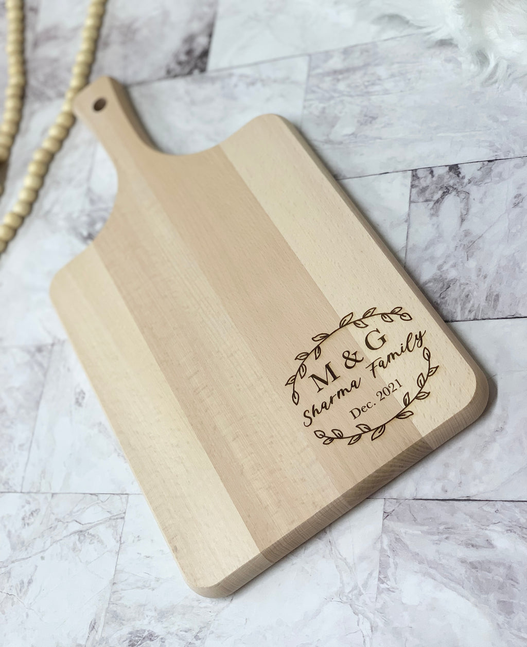 Natural wooden personalized cutting board with engraved family name and date on smooth wood grain surface