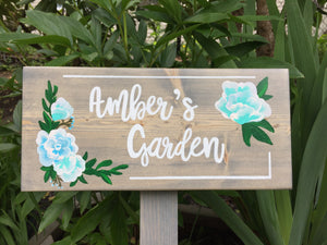 Large custom wooden garden sign with white cursive letters and blue floral illustrations on natural wood background
