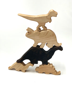 Stacked natural and dark wooden dinosaur toy figurines on white background for imaginative play and motor skills development