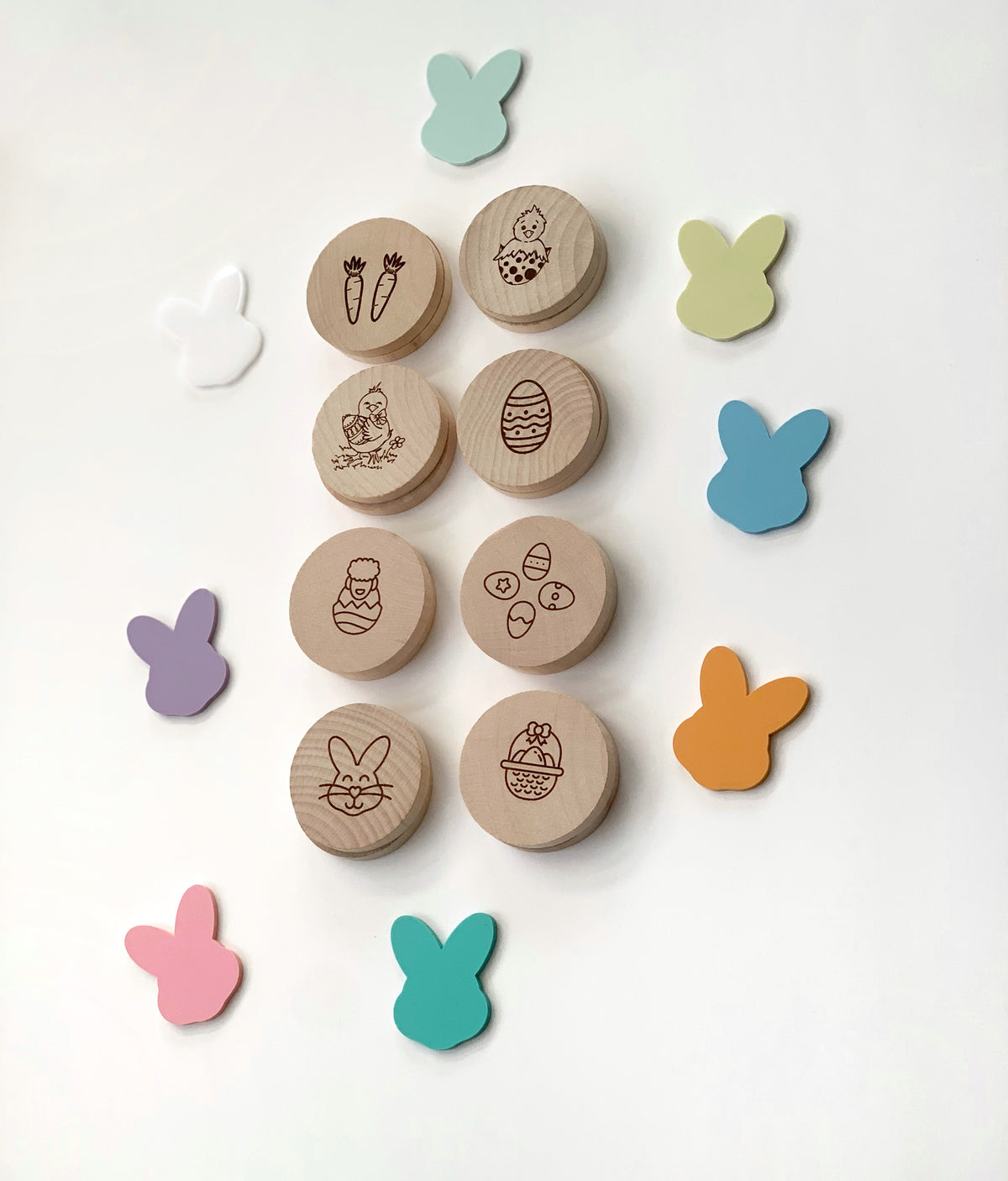 Round wooden Easter memory game pieces with engraved holiday images surrounded by colorful bunny shapes on white background