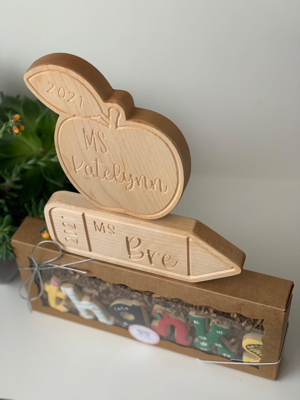 Personalized wooden teacher nameplate with apple and pencil shapes engraved with names and year on natural wood
