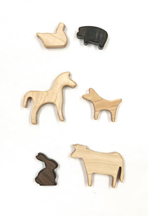 Set of small natural and dark wood farm animal toy figurines on white background