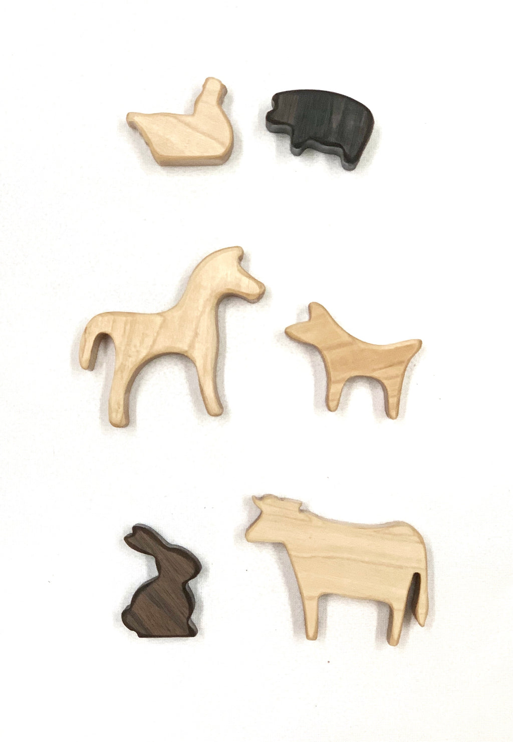 Set of small natural and dark wood farm animal toy figurines on white background
