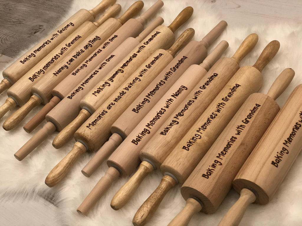 Collection of personalized wooden rolling pins with custom messages wood burned along the length of each pin