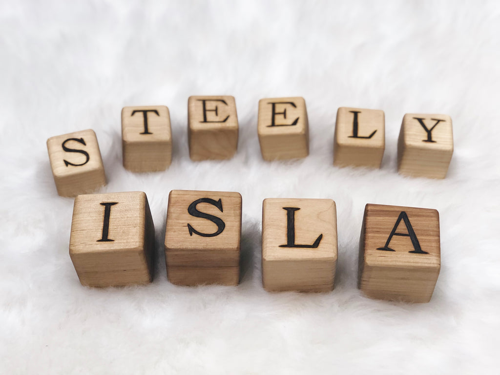 Natural 1.5-inch custom wood blocks with engraved black capital letters arranged on white fluffy background