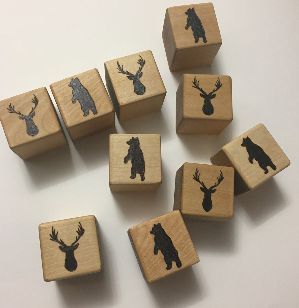 Natural wooden 1.5-inch blocks scattered with engraved black bear and deer head silhouettes on white background