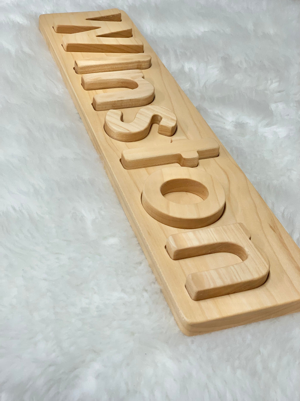 Personalized natural hardwood name puzzle with uppercase and lowercase letters on white textured background