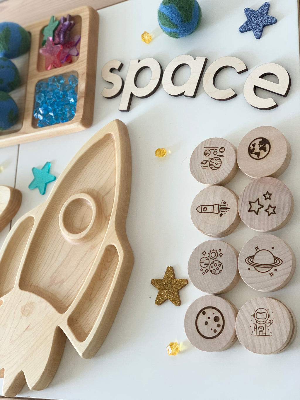 Wooden space themed memory game discs with engraved planets, rocket, astronaut, and stars next to wooden rocket tray and letters spelling space