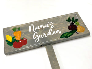 Large custom wooden garden sign painted gray with white cursive letters and colorful vegetable illustrations on wood grain background
