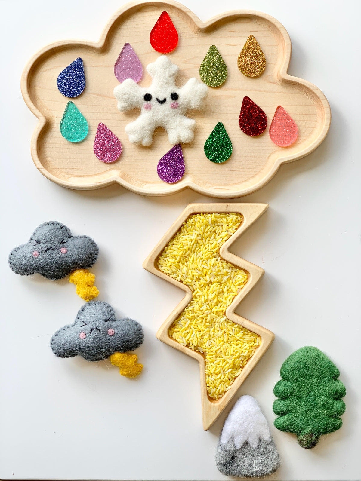 Wooden cloud-shaped tray with colorful glitter raindrops and felt snowflake, with lightning tray filled with yellow rice and felt weather pieces