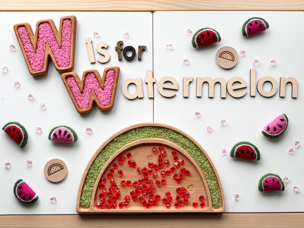 Wooden alphabet sensory tray with W letter, watermelon theme, pink letter beads, and felt watermelon pieces on white background