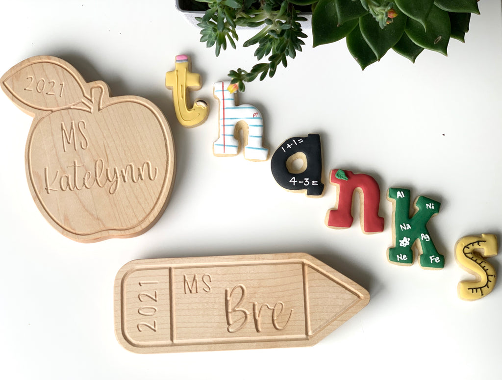 Natural wooden personalized teacher name plates shaped like an apple and pencil with colorful alphabet letters on white background
