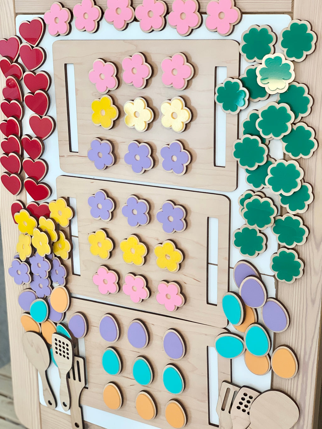 Wooden cookie sheet with colorful flower, heart, egg, and leaf-shaped cookies with attached Velcro pieces on wooden surface