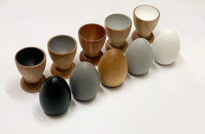 Natural wooden eggs and matching cups in neutral tones for Montessori-inspired color sorting and educational play.