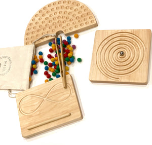 Set of natural wooden tracing boards with engraved lines, colorful felt balls, and wooden tweezers on white background