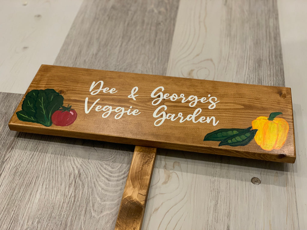 Personalized large wooden vegetable garden sign with white cursive lettering and painted colorful vegetable illustrations on natural wood