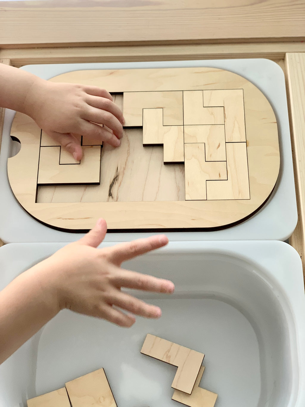Small Flisat table top insert with natural wood puzzle pieces being assembled by child’s hands