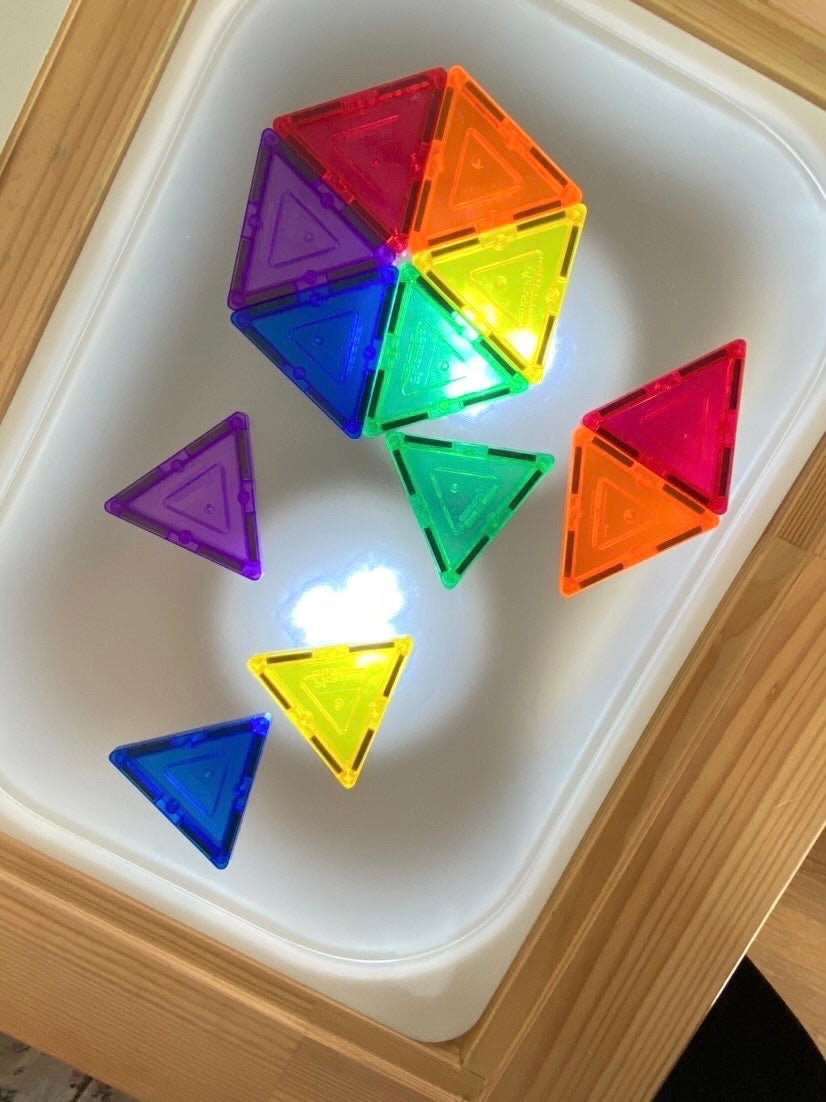 Small frosted acrylic Flisat table top insert with colorful translucent magnetic triangles on wooden frame background