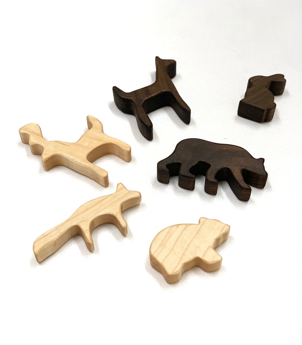 Set of six small natural and dark brown wooden woodland animal toy figurines on white background