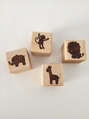Natural wooden 1.5-inch custom blocks with engraved animal silhouettes of elephant, monkey, lion, and giraffe on white background