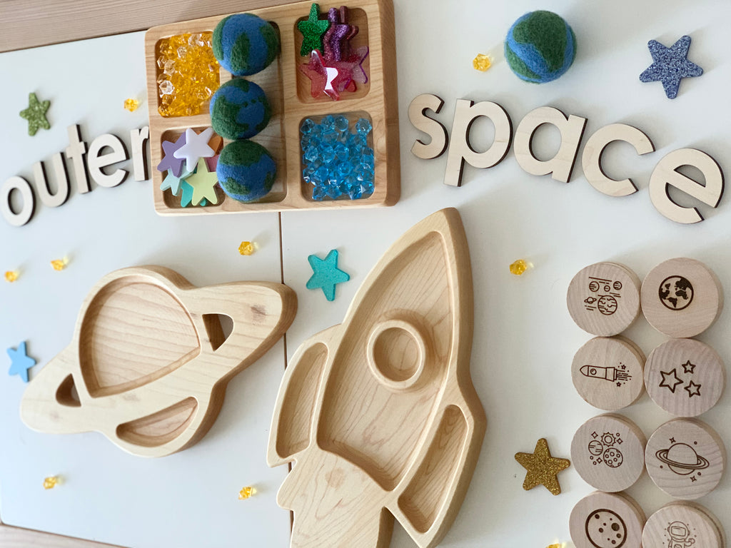 Wooden space-themed memory game pieces including rocket, planet tray, earth felt balls, and round discs with space illustrations on white surface