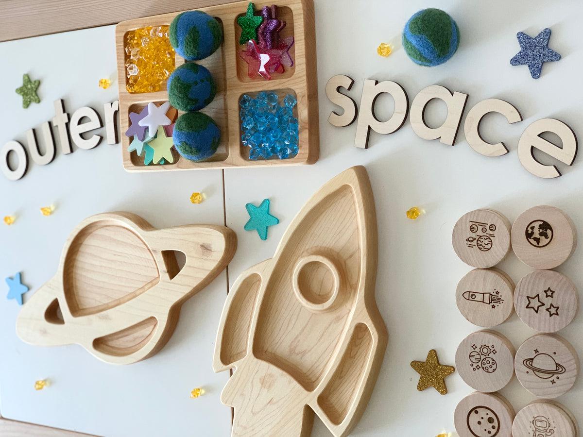 Wooden space-themed memory game pieces including rocket, planet tray, earth felt balls, and round discs with space illustrations on white surface