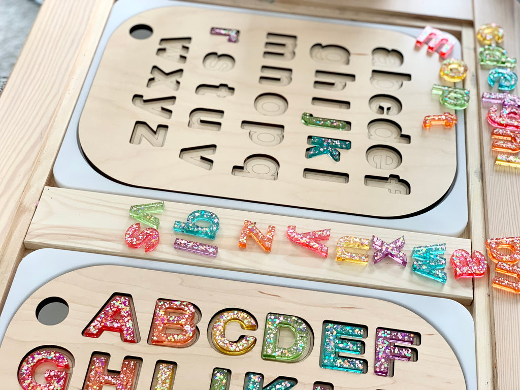 Wooden Flisat table top insert with uppercase resin alphabet letters in colorful glitter inside letter slots on light wood surface