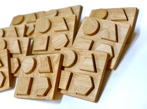 Natural wooden shape puzzle tiles with raised geometric shapes for kids learning motor skills and shape recognition on white background