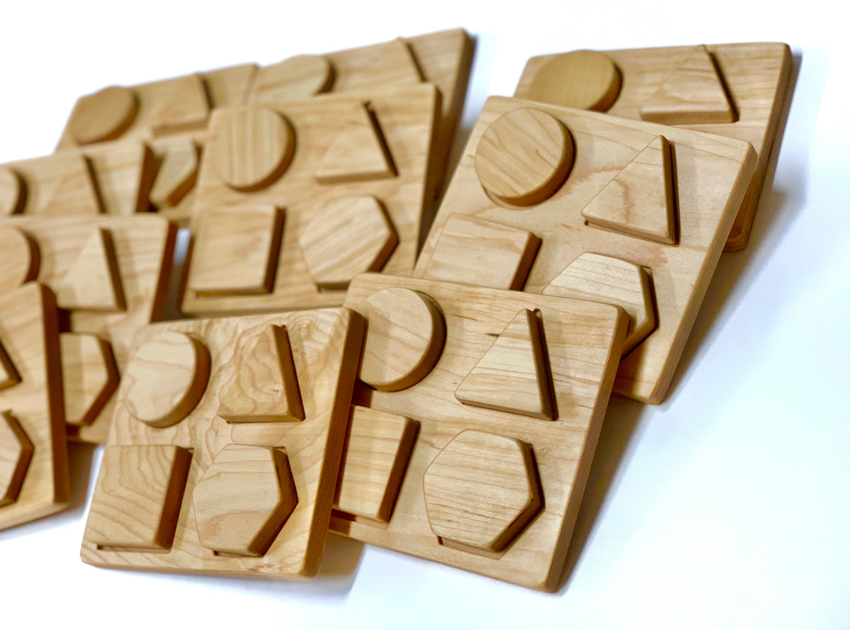 Natural wooden shape puzzle tiles with raised geometric shapes for kids learning motor skills and shape recognition on white background