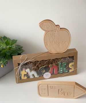 Personalized wooden teacher name plate shaped like an apple and pencil with engraved names and year on light background