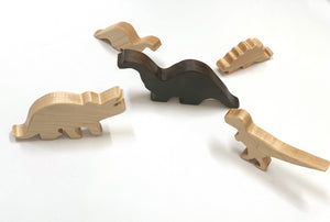 Set of five handcrafted wooden dinosaur toy figurines in natural and dark wood tones on white background