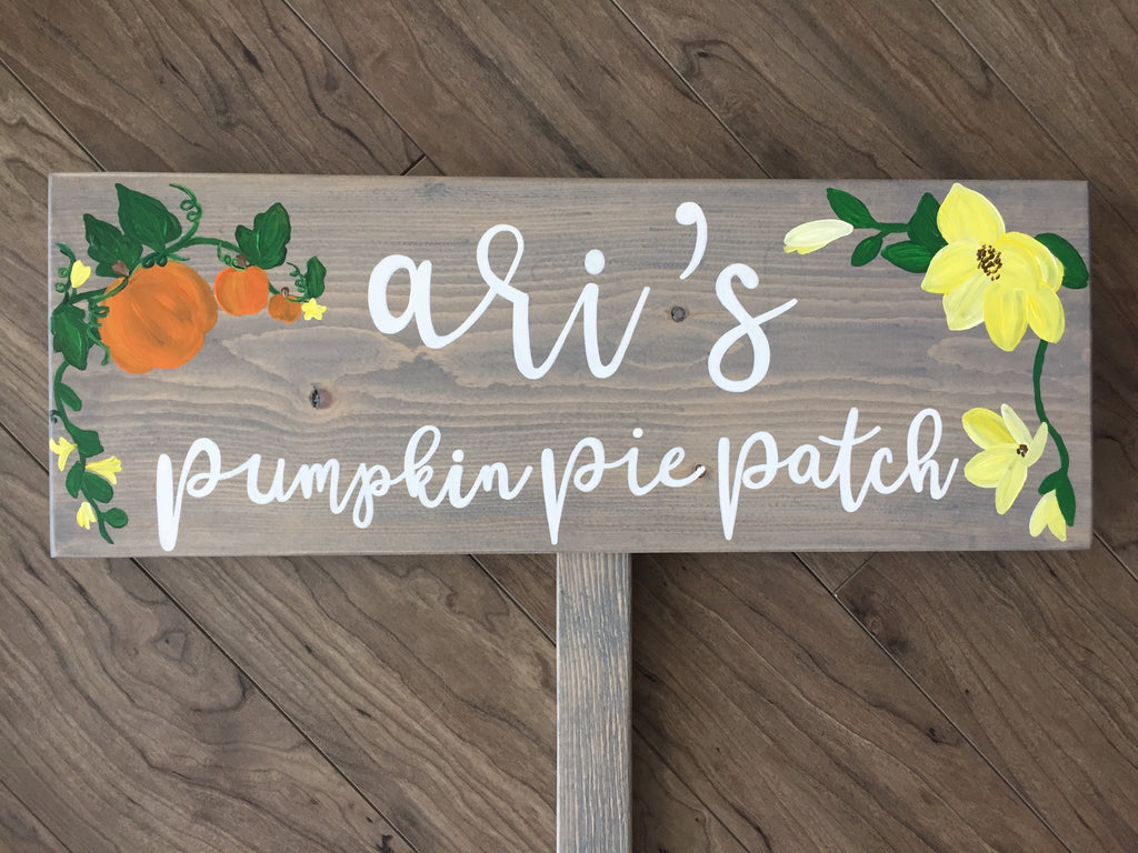 Personalized wooden garden sign with white cursive letters and painted pumpkins and yellow flowers on natural wood background
