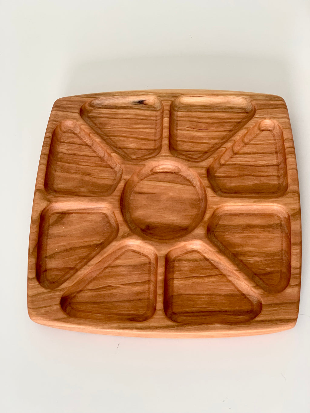 Square wooden sensory tray with sun ray-inspired divided sections on white background