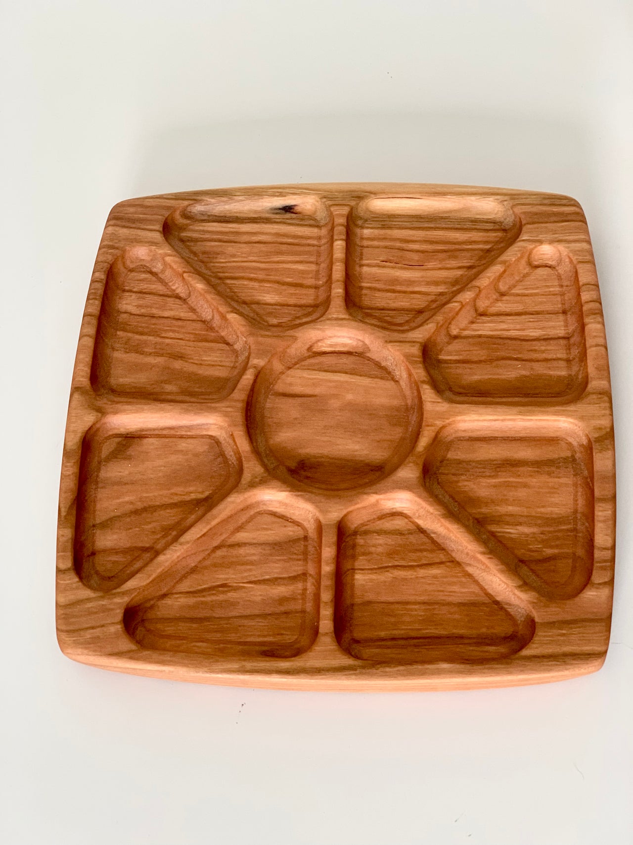 Square wooden sensory tray with sun ray-inspired divided sections on white background